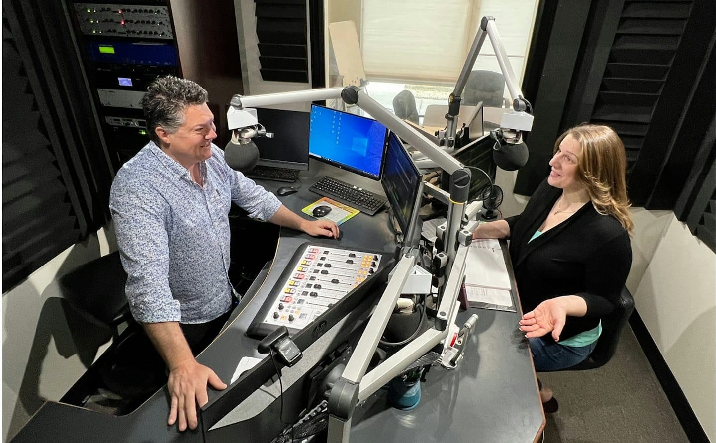 Dos personas discuten un proyecto en un estudio de radio profesional.