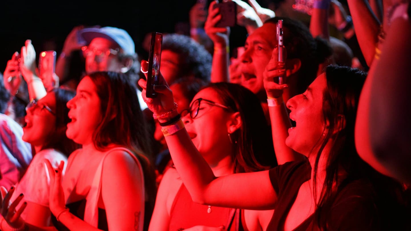Los asistentes a un concierto animan mientras graban la actuación en sus teléfonos inteligentes.