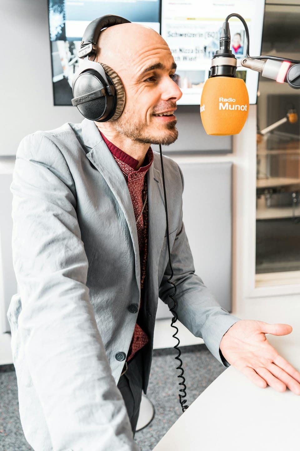 Hombre con auriculares hablando a un micrófono en un estudio.