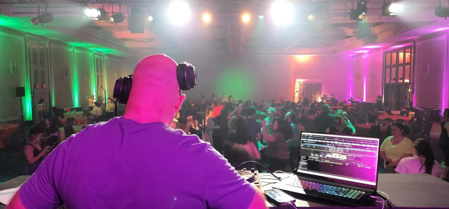 DJ usando una laptop y mezcladora en una fiesta.