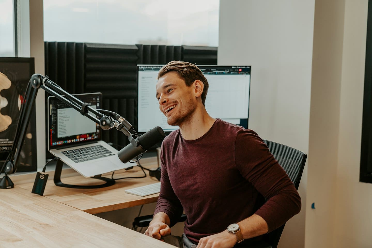 Hombre joven riendo mientras graba un podcast en un estudio.